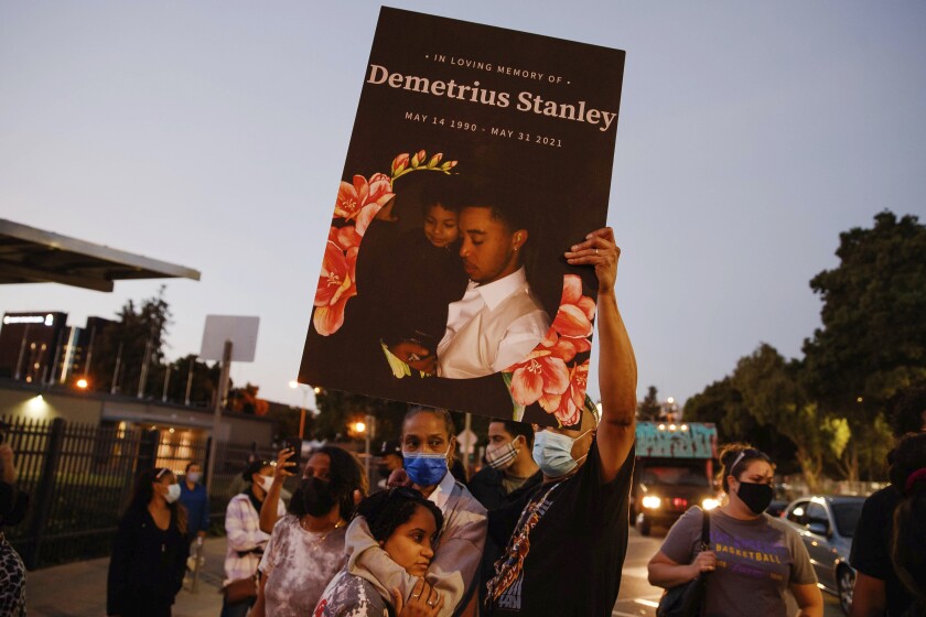 A sign with Demetrius Stanley's image on it is held up during a protest in San Jose, Calif., on Tuesday, June, 1, 2021. Police in California have released images of a Black man holding a pistol and aiming it at an unmarked police car before he was killed in a confrontation with officers in San Jose. Officials released the images Tuesday, shortly before more than 100 demonstrators marched along streets and a freeway to protest the Memorial Day shooting of 31-year-old Stanley. (Randy Vazquez/Bay Area News Group via AP)