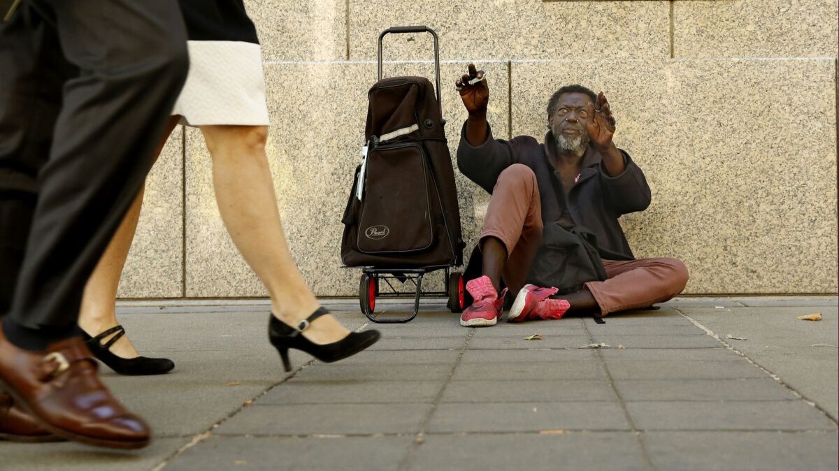 Carl Wallace, who says he is homeless and lives on the streets, waves to people passing by in Sacramento on Wednesday. The latest point-in-time count shows the number of people who are homeless in Sacramento County increased by 19% over the last two years.