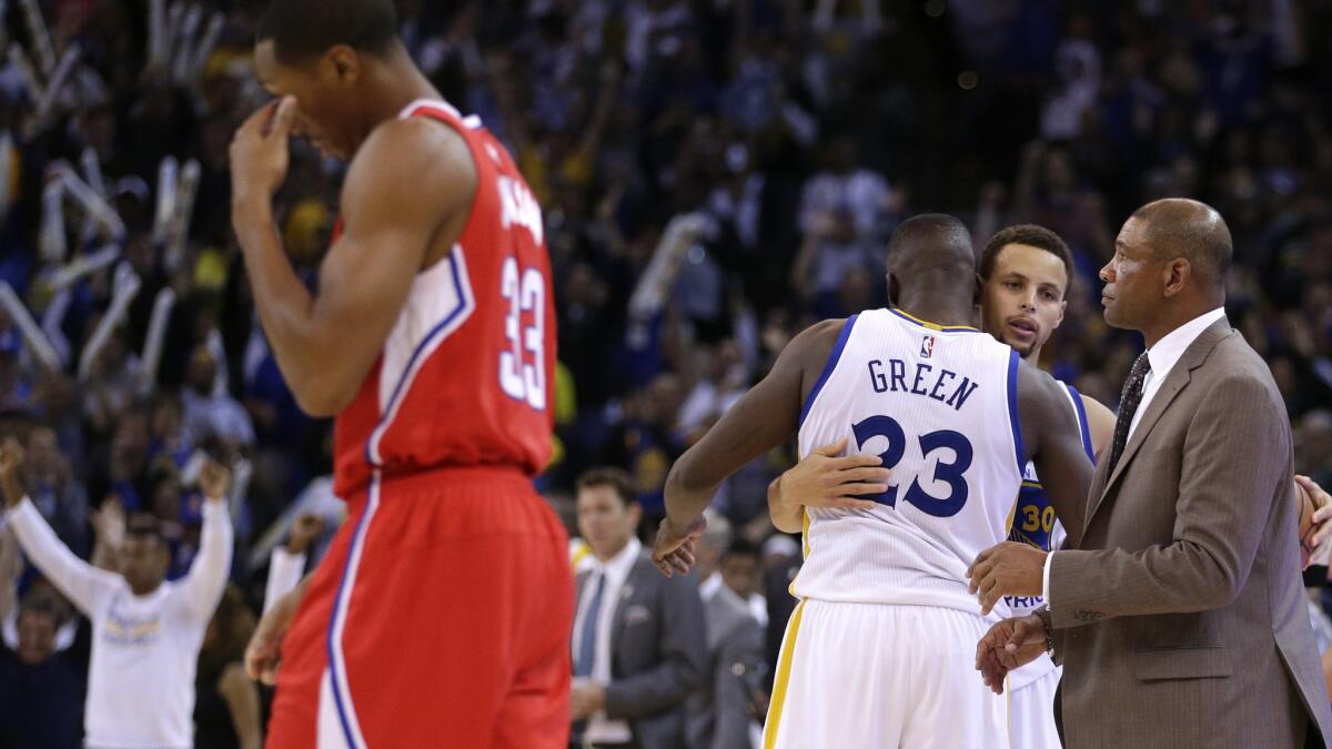Warriors point guard Stephen Curry and forward Draymond Green (23) embrace after defeating Wesley Johnson (33) and the Clippers on Wednesday night.