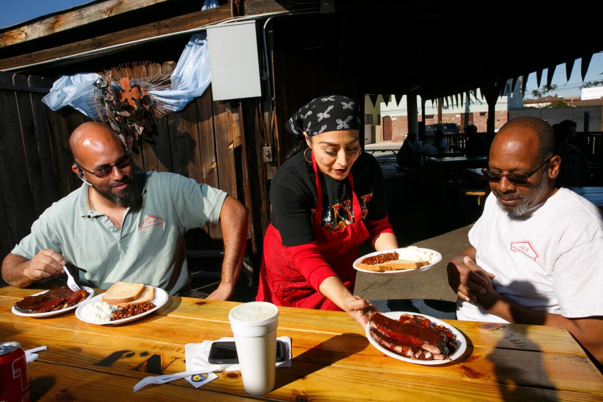Otis Robinson, left, and Stafford Floyd get their meal served at JNJ Bar-B-Que and Burgers at the front of Adams Gateway in South Los Angeles.