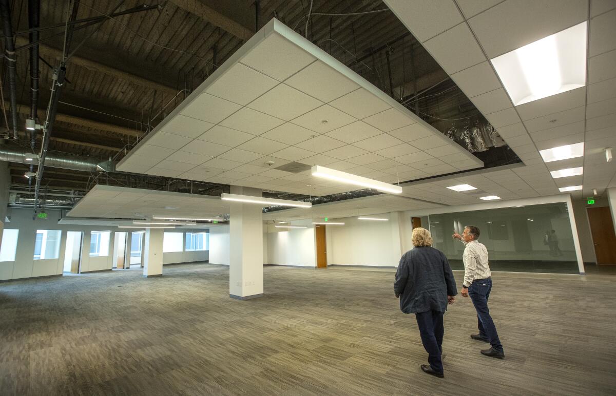 Two men walking through an empty building.