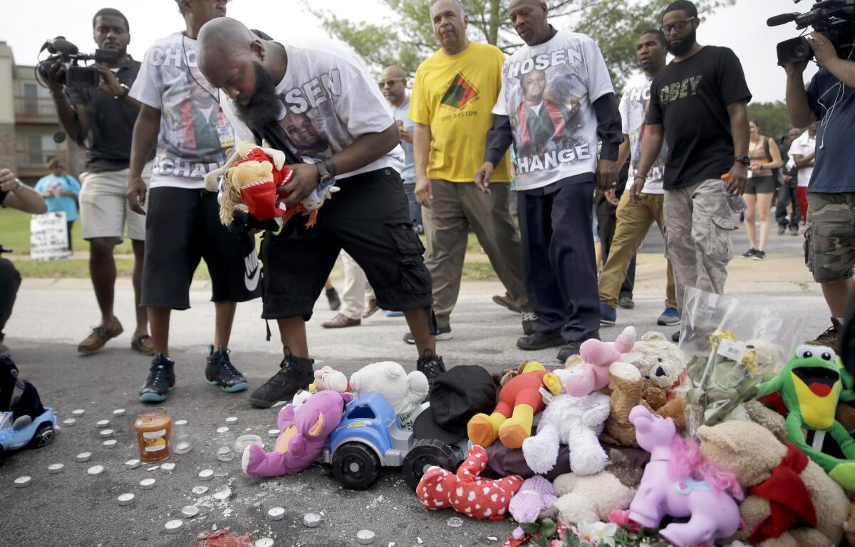 Michael Brown Sr. drops off stuffed animals at a memorial to his son, Michael Brown, before taking part in a parade in his son's honor Saturday in Ferguson, Mo.
