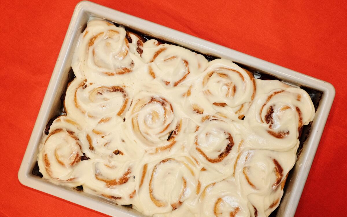 A rectangular pan containing a dozen frosted cinnamon buns