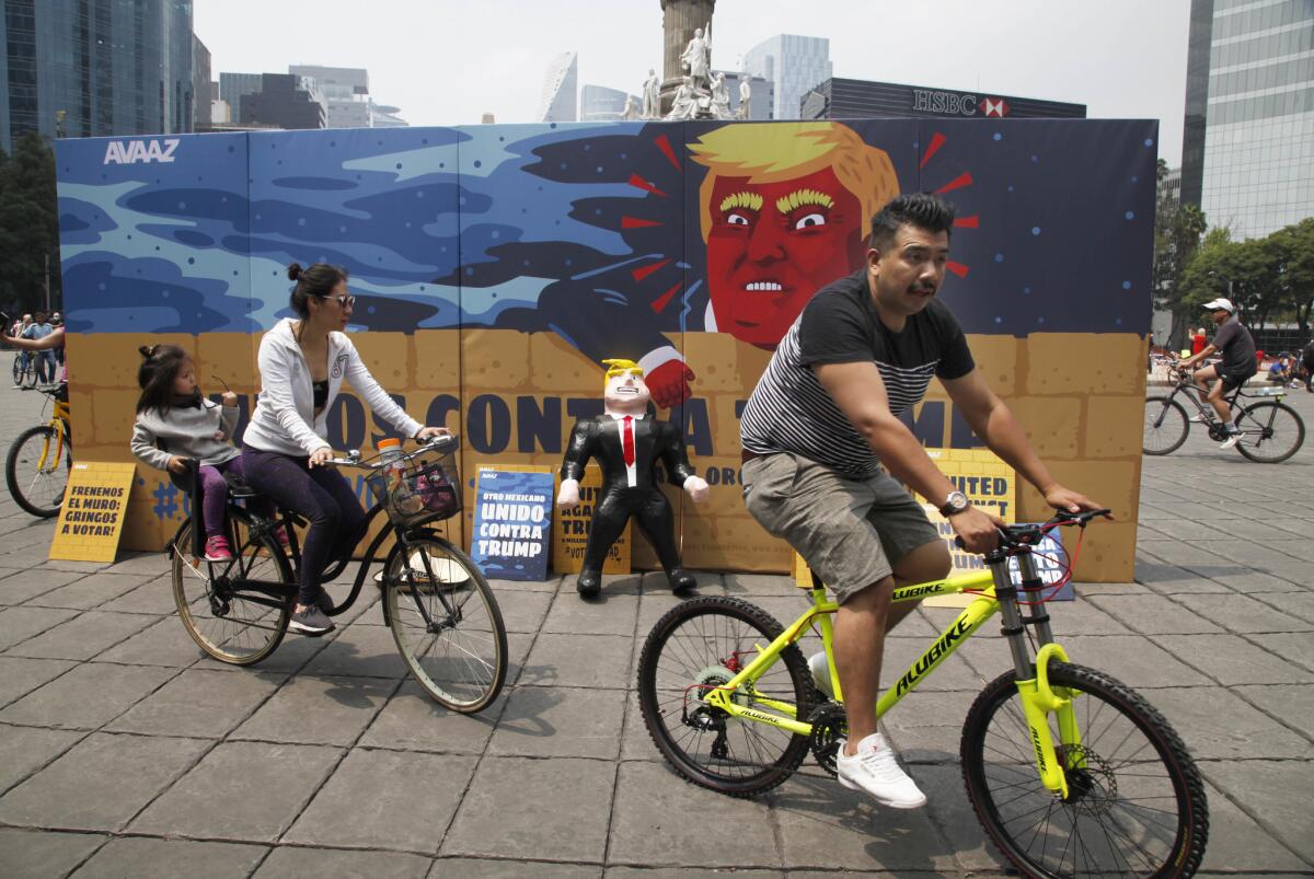 A family rides their bicycles past a piñata depicting U.S. presidential nominee Donald Trump in Mexico City.
