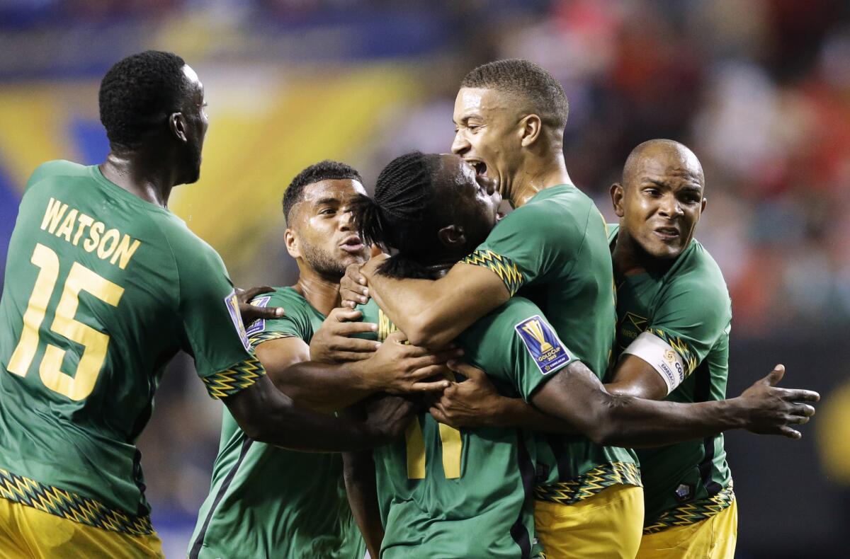 Jamaica’s Darren Mattocks, center, is embraced by teammate Michael Hector after scoring a goal against the U.S. in the first half of a Gold Cup semifinal Wednesday in Atlanta.