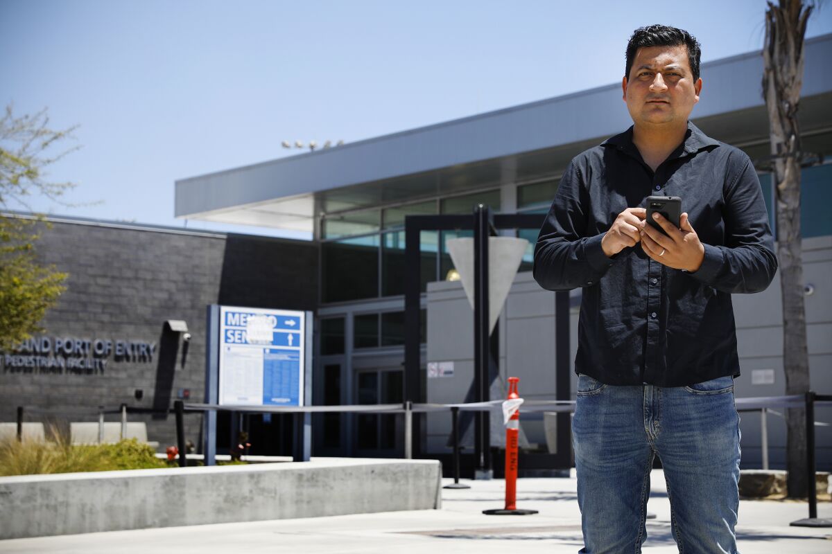 Christian Ramirez, a San Diego border rights activist, poses with a cellphone at the border.