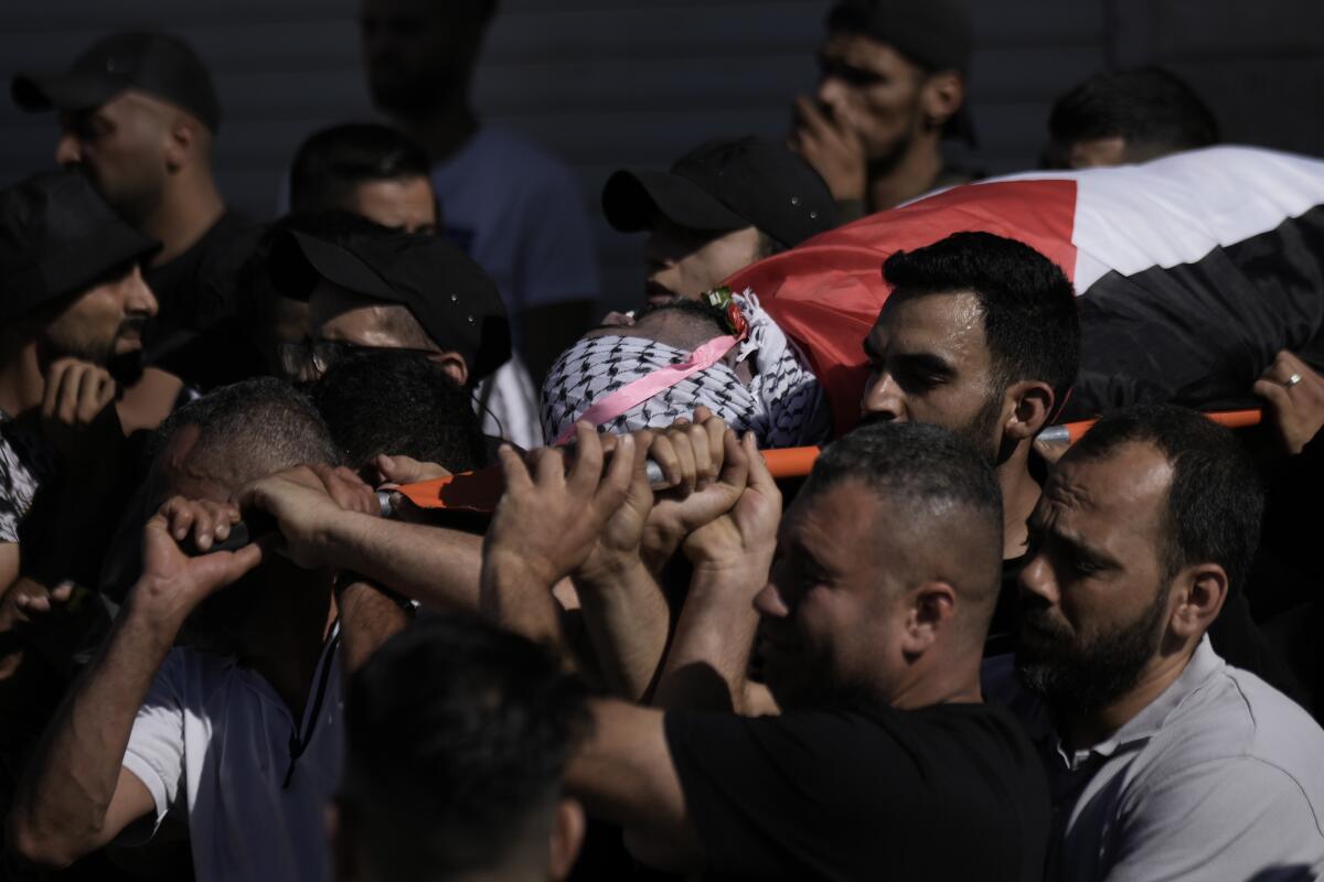 Palestinian mourners carry a body.