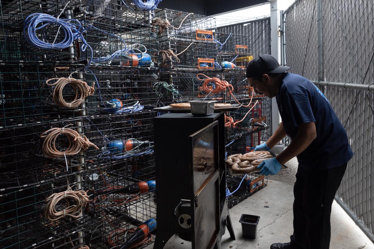 A man loads sausage into a smoker.