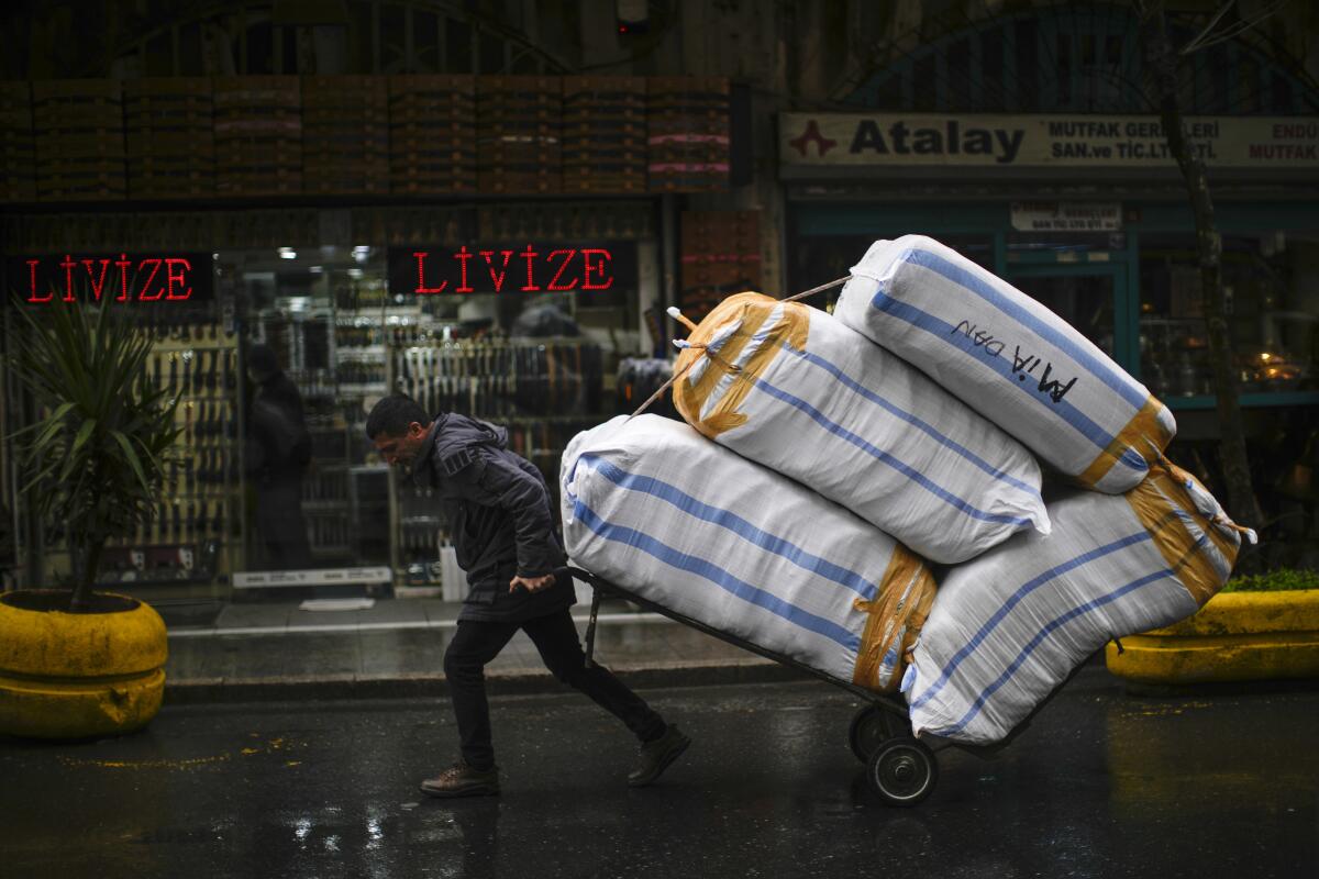 A man pulls a trolley with goods in a commercial area in Istanbul, Turkey, Wednesday, Jan. 12, 2022. Turkey's government and central bank have taken a series of complex steps in recent weeks to prop up a beleaguered economy crippled by skyrocketing consumer prices, instead of ending a much-criticized plan to cut interest rates. (AP Photo/Francisco Seco)