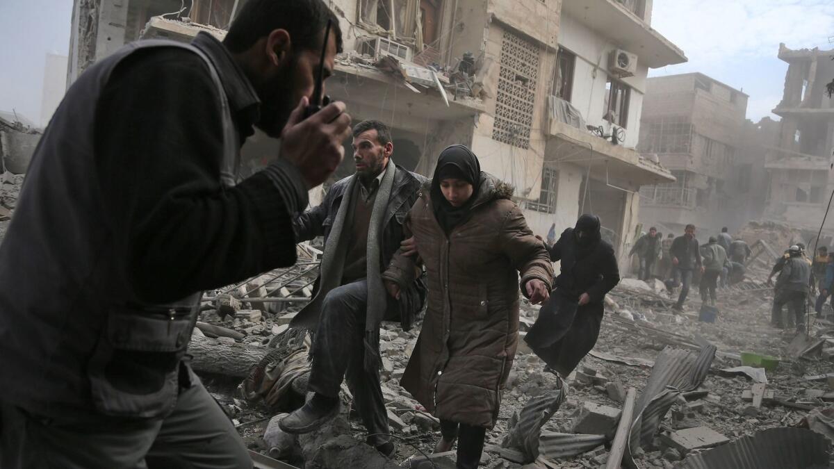 A Syrian civil defense volunteer speaks on a wireless transmitter as other civilians flee an area hit by a reported government airstrike in the rebel-held town of Saqba, in the besieged east Ghouta region on the outskirts of Damascus, on Feb. 20, 2018.