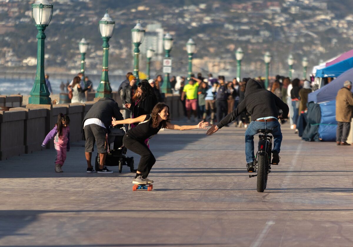A passing high five, skater to cyclist.  