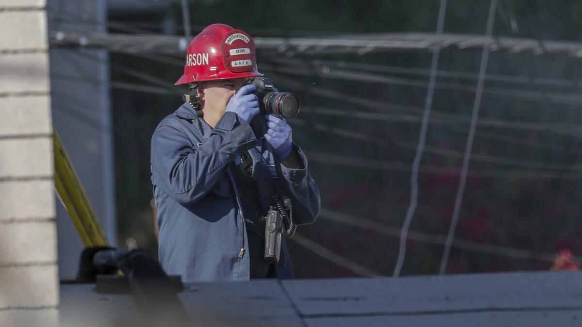 A fire investigator surveys the scene after a Studio City fire erupted at a music recording studio Saturday, killing two people and two others with grave injuries. Efrem Demery, 28, was arrested and booked on suspicion of murder with special circumstances.