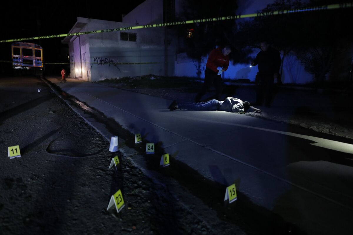 A paramedic and police officer look at the body of a man, estimated to be about 28, found with five gunshot wounds to his back and legs in Tijuana on Dec. 30, 2018.