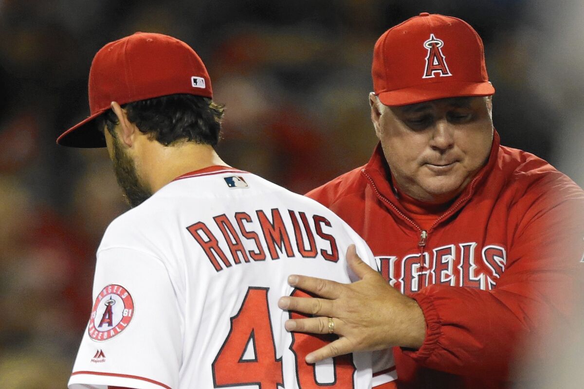 Angels manager Mike Scioscia pats pitcher Cory Rasmus on the back as he removes him from a game on Apr. 8.