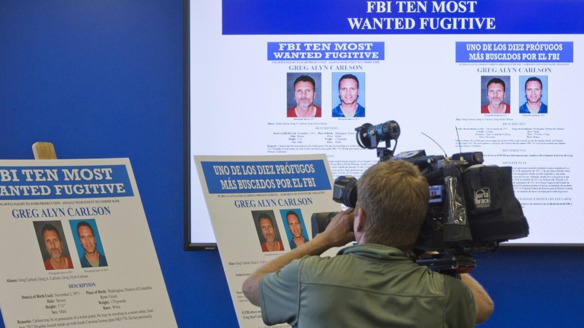 A television cameraman films the photographs of Greg Alyn Carlson during a news conference at the FBI headquarters in Los Angeles.