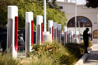 SANTA MONICA, CA - APRIL 17, 2024 - A man stands next to a row of Tesla charging towers at a Tesla Supercharger station at the corner of 14th St. and Santa Monica Blvd. in Santa Monica on April 17, 2024. Tesla Inc. is laying off more than 10% of its workforce, Chief Executive Elon Musk wrote in an email to staff. Musk cited job overlap and the need to reduce costs, according to the email sent last Sunday. Bloomberg News estimated that the layoffs would affect more than 14,000 employees. (Genaro Molina/Los Angeles Times)