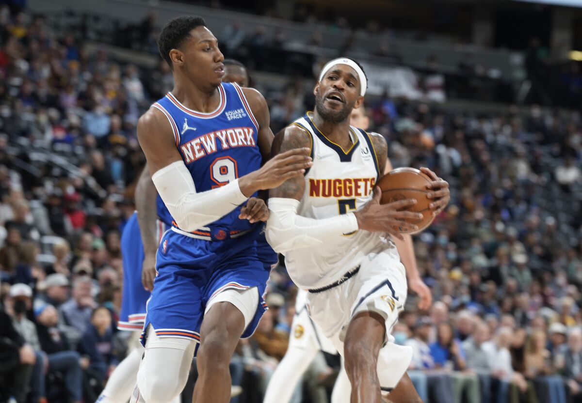 Denver Nuggets forward Will Barton, right, is defended by New York Knicks guard RJ Barrett during the second half of an NBA basketball game Tuesday, Feb. 8, 2022, in Denver. The Nuggets won 132-115. (AP Photo/David Zalubowski)
