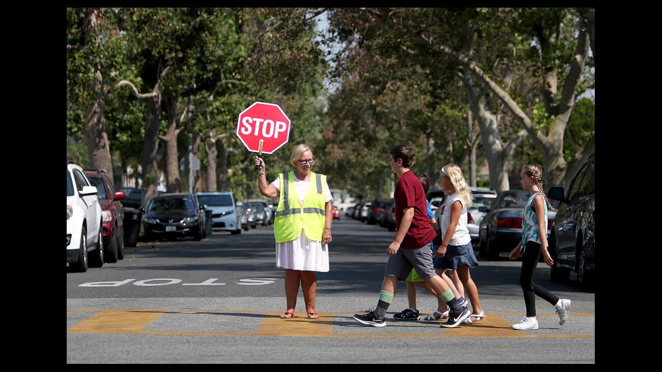 Community volunteer Linda Walmsley shows children how to properly cross the street with the aid of a crossing guard during the Auto Club, Burbank Unified School District and Burbank Police event on traffic safety skills, in time for the new school year, in front of Jordan Middle School in Burbank on Thursday, Aug. 9, 2018.