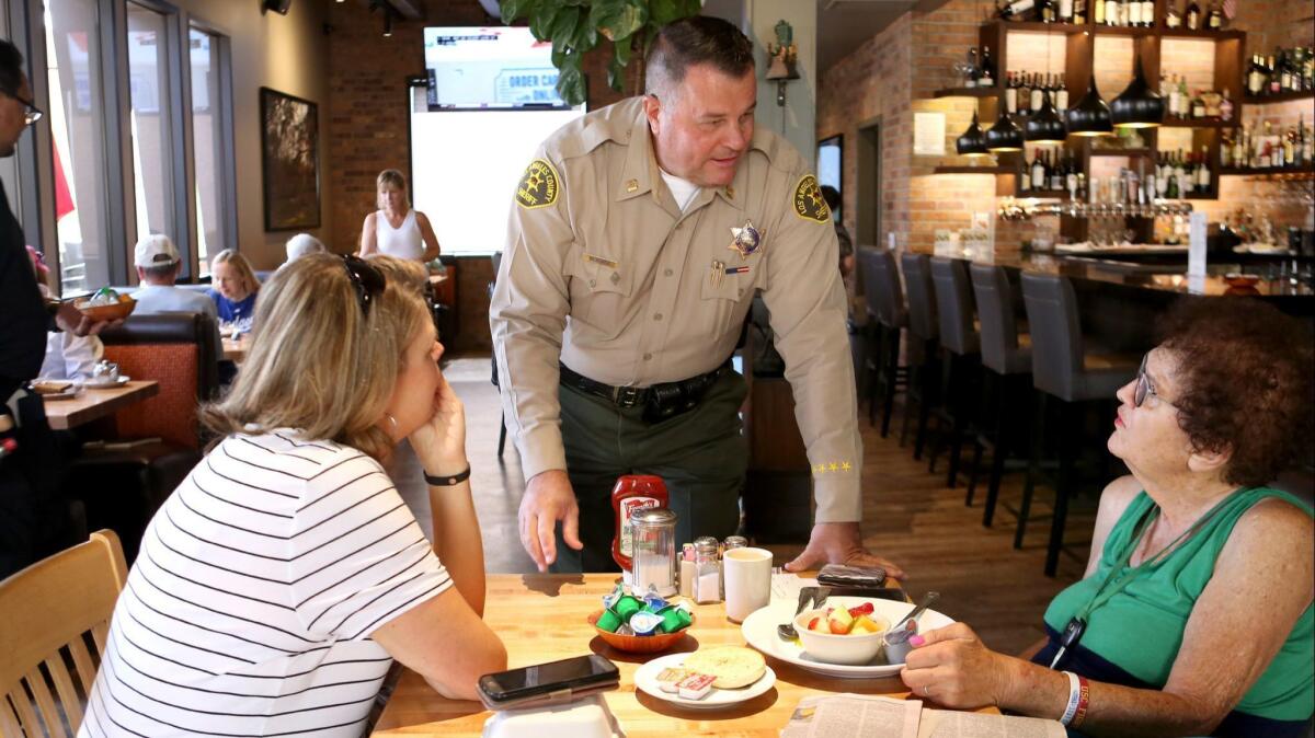 Crescenta Valley Sheriff station Cptn. Chris Blasnek speaks with La Cañada Flintridge resident Harriet Hammons, right, as Heidi Moreno looks on, during the annual Tip-A-Cop event at Hill Street Cafe, in La Canada Flintridge on Friday, Aug. 17, 2018.