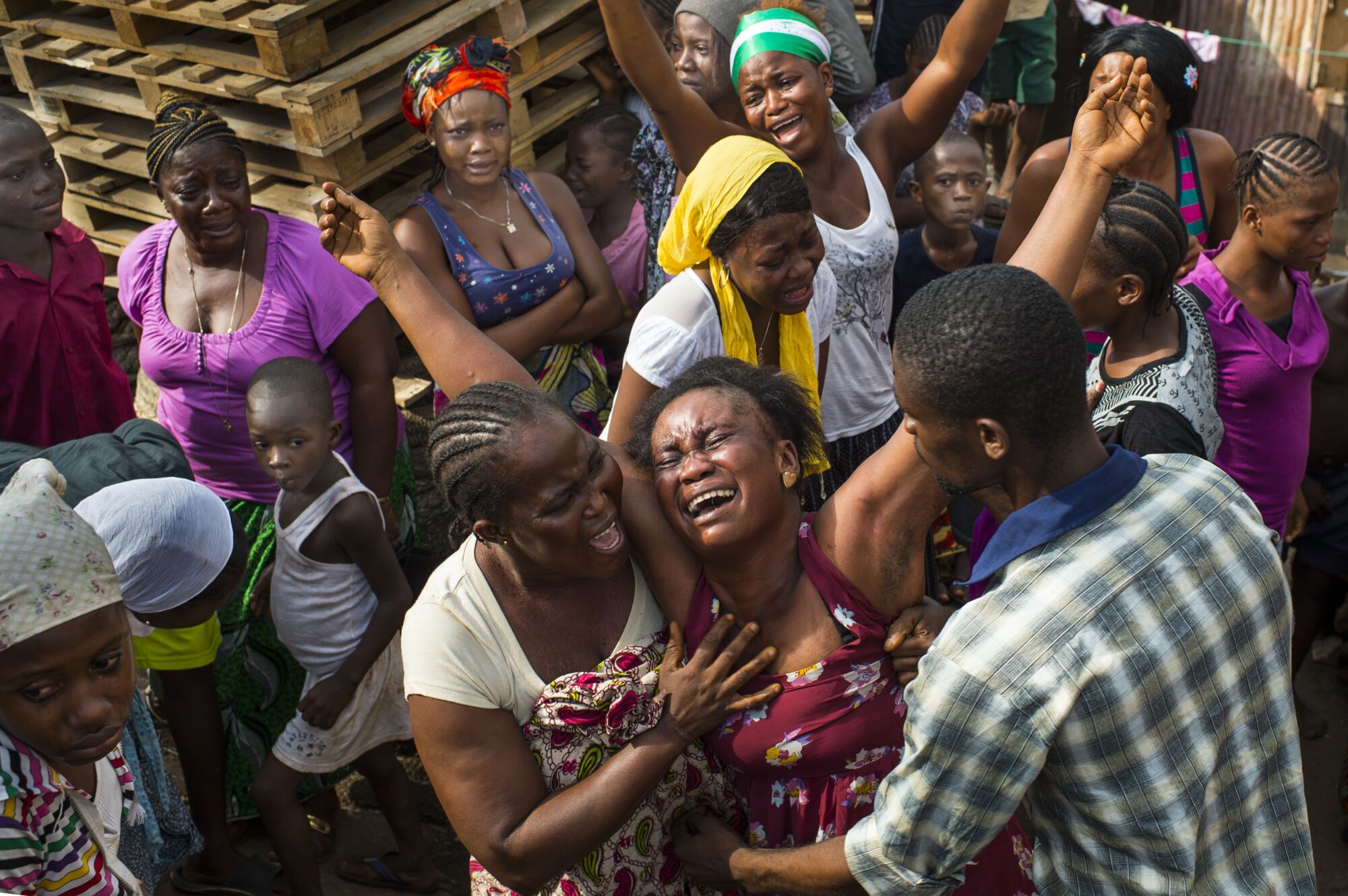 People comfort a grief-stricken woman in Freetown, Sierra Leone, in 2014.