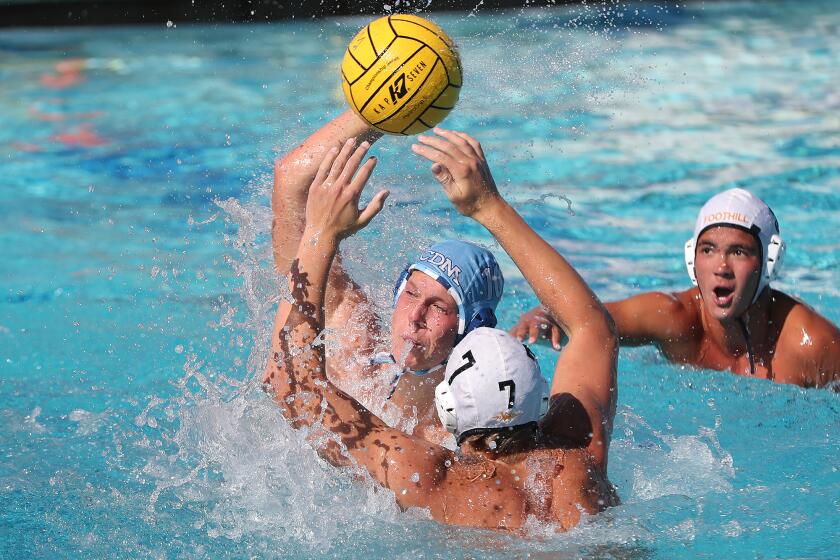 Cooper Harlan (10) of Corona del Mar gets a shot off for a quick goal as Russell Lowe (7) tries to stop him, during a nonleague waterpolo match against Foothill on Tuesday.