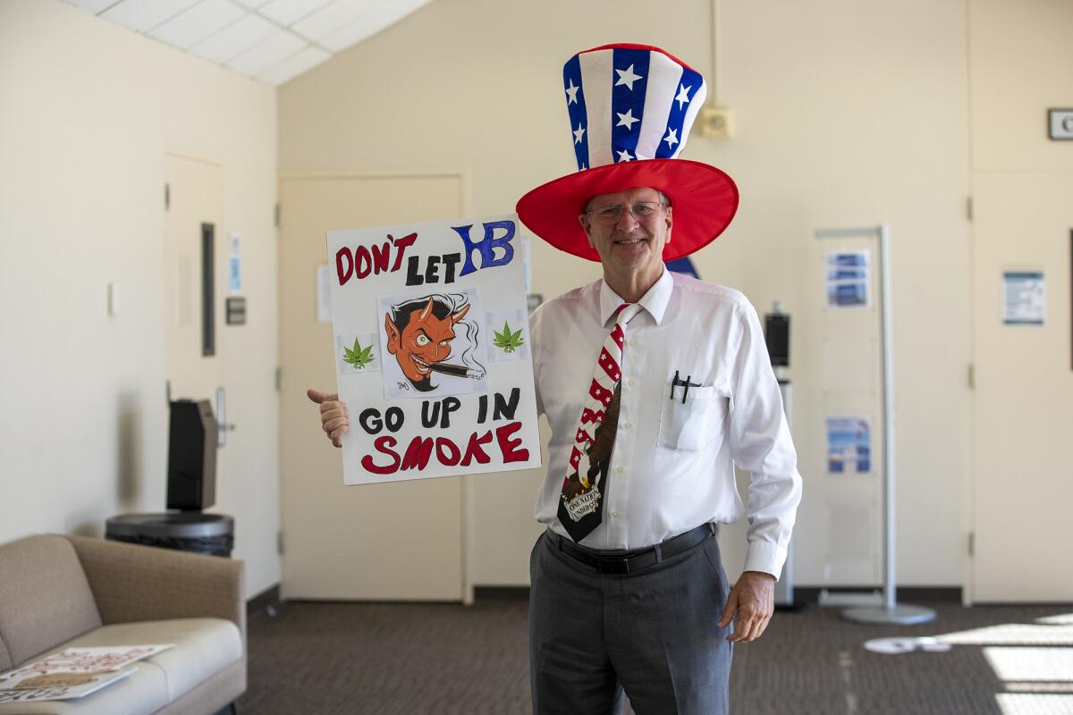 Russell Neal poses with an anti-cannabis sign outside of Huntington Beach City Council chambers.