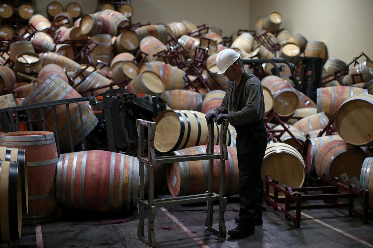 Cellar worker Adam Craig moves a wine rack as he cleans up barrels that collapsed in a storage room at Kieu Hoang Winery on Aug. 25 in Napa.