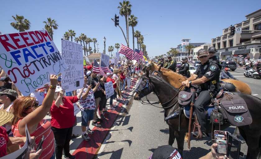 Mounted police line up to keep protesters on the sidewalk as thousands of protesters rally at the intersection of Main Street and Pacific Coast Highway in Huntington Beach.
