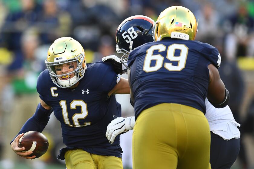 SOUTH BEND, INDIANA - SEPTEMBER 28: Ian Book #12 of the Notre Dame Fighting Irish is sacked by Eli Hanback #58 of the Virginia Cavaliers during the second half at Notre Dame Stadium on September 28, 2019 in South Bend, Indiana. (Photo by Stacy Revere/Getty Images) ** OUTS - ELSENT, FPG, CM - OUTS * NM, PH, VA if sourced by CT, LA or MoD **