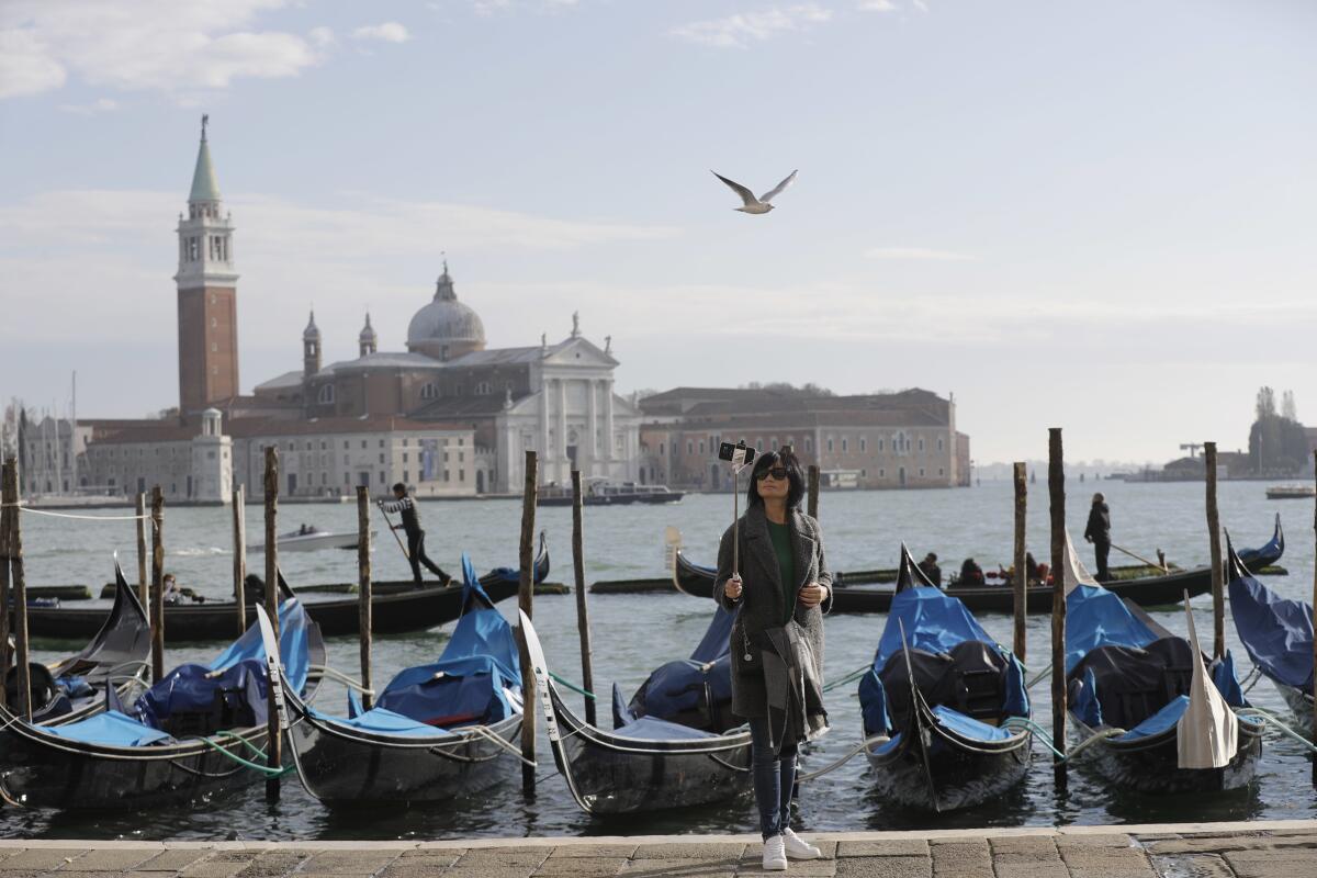 ARCHIVO - Un turista se toma una selfie en la plaza de San Marcos, Venecia,