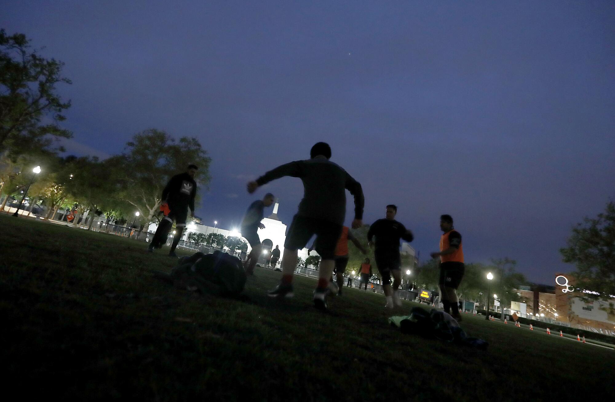 Men play soccer, violating social distancing restrictions, near the Los Angeles Memorial Coliseum in Exposition Park.