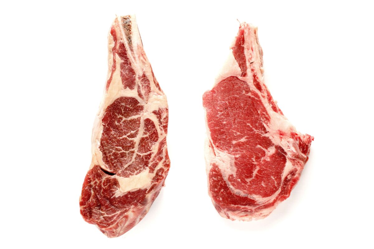 A bone-in ribeye steak from Mindful Meats (left) and a USDA choice bone-in ribeye steak from Ralphs.