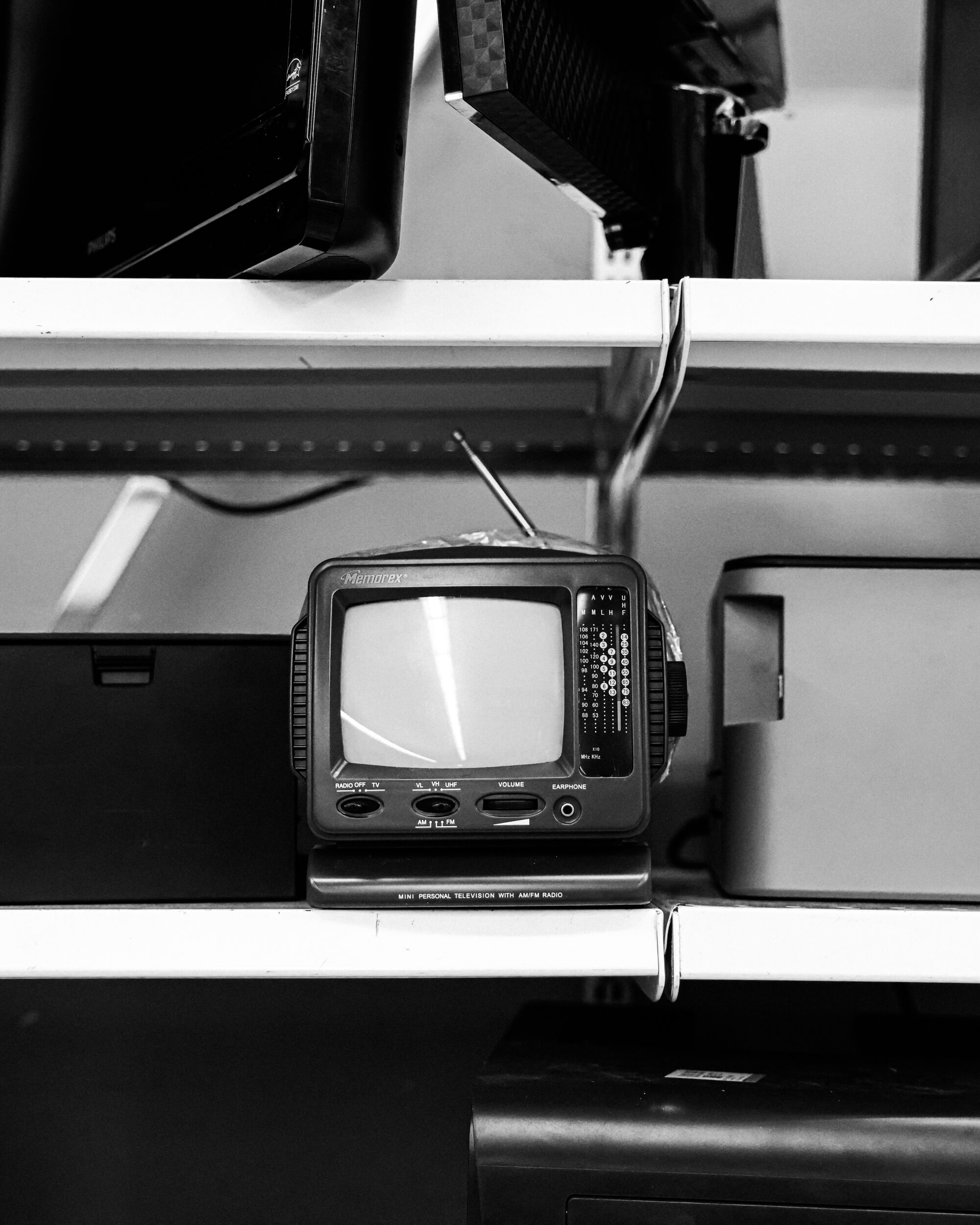 A black-and-white photo of a small antique TV on a shelf