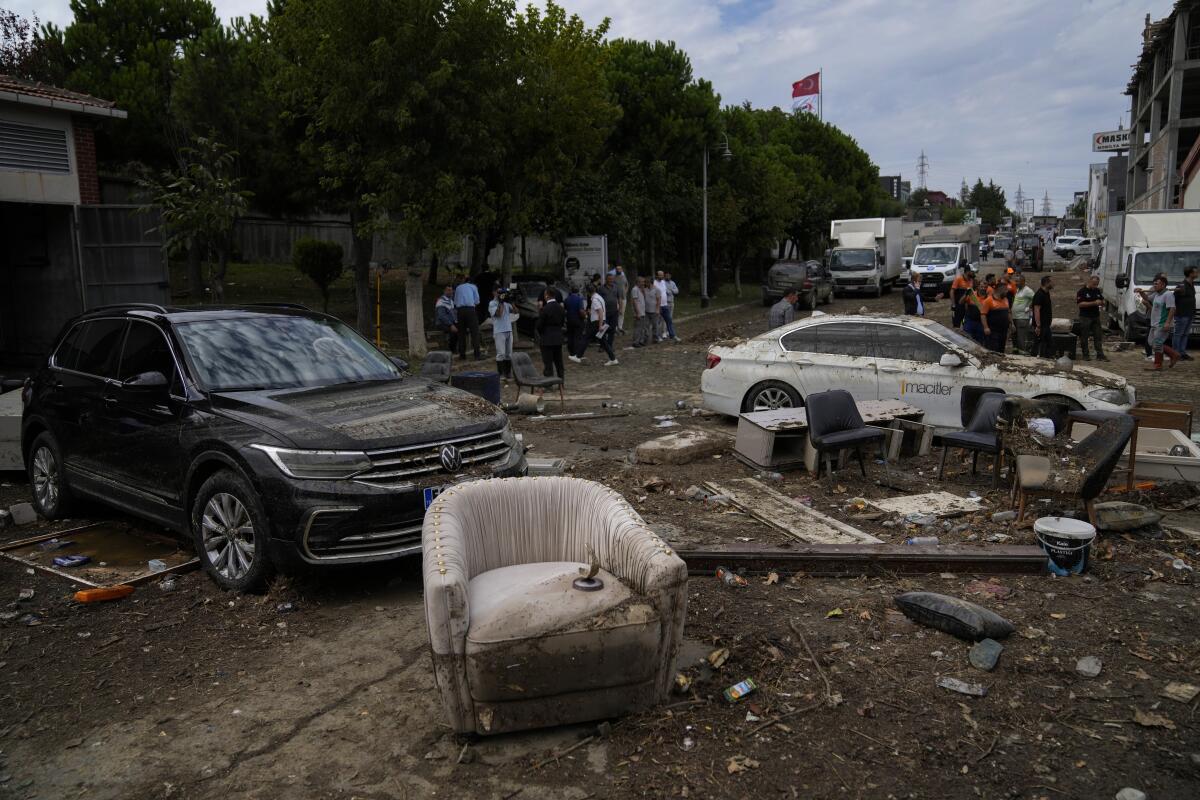 Vehicles and furniture strewn in a street after floods
