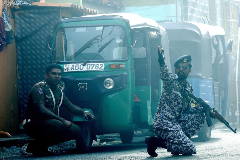 Security personnel react as a device is detonated in a van near the St. Anthony's Church shrine in Colombo, Sri Lanka.