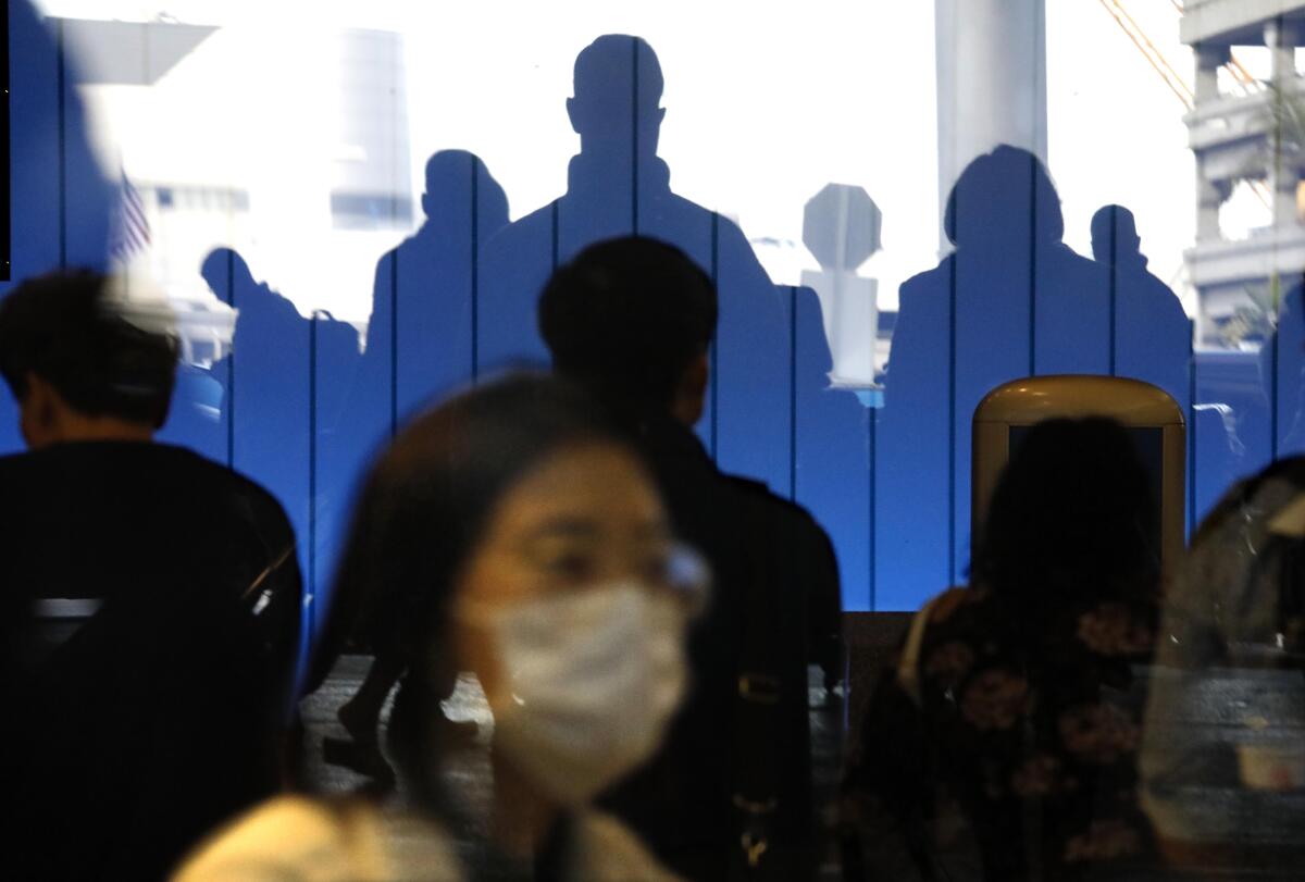 A traveler wearing a mask passes through the Tom Bradley International Terminal at LAX.