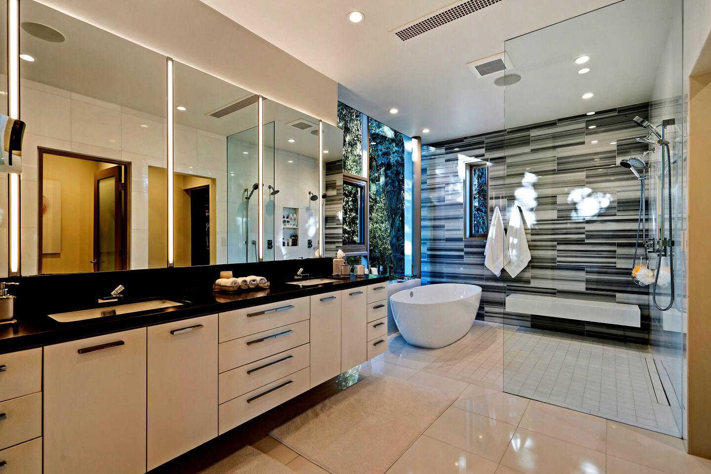 A large bathroom with sinks, a freestanding bathtub and a shower.