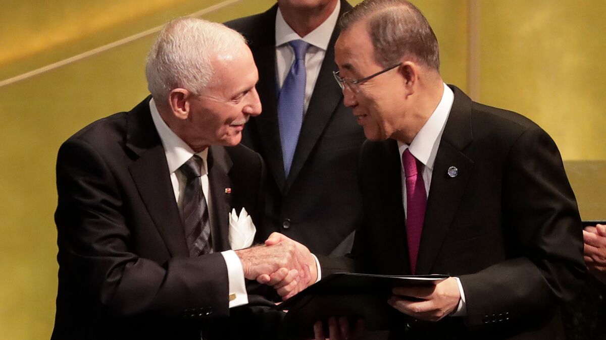 William Lacy Swing, left, director general of the International Organization for Migration, on Monday shakes hands with U.N. Secretary-General Ban Ki-moon after signing documents at U.N. headquarters in New York.