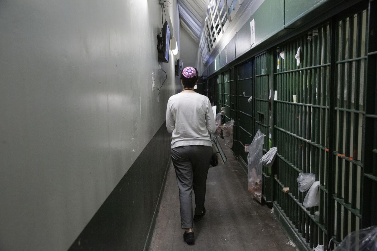 Los reclusos llaman a Erlick mientras camina por una hilera de celdas. (Liz Moughon / Los Angeles Times)