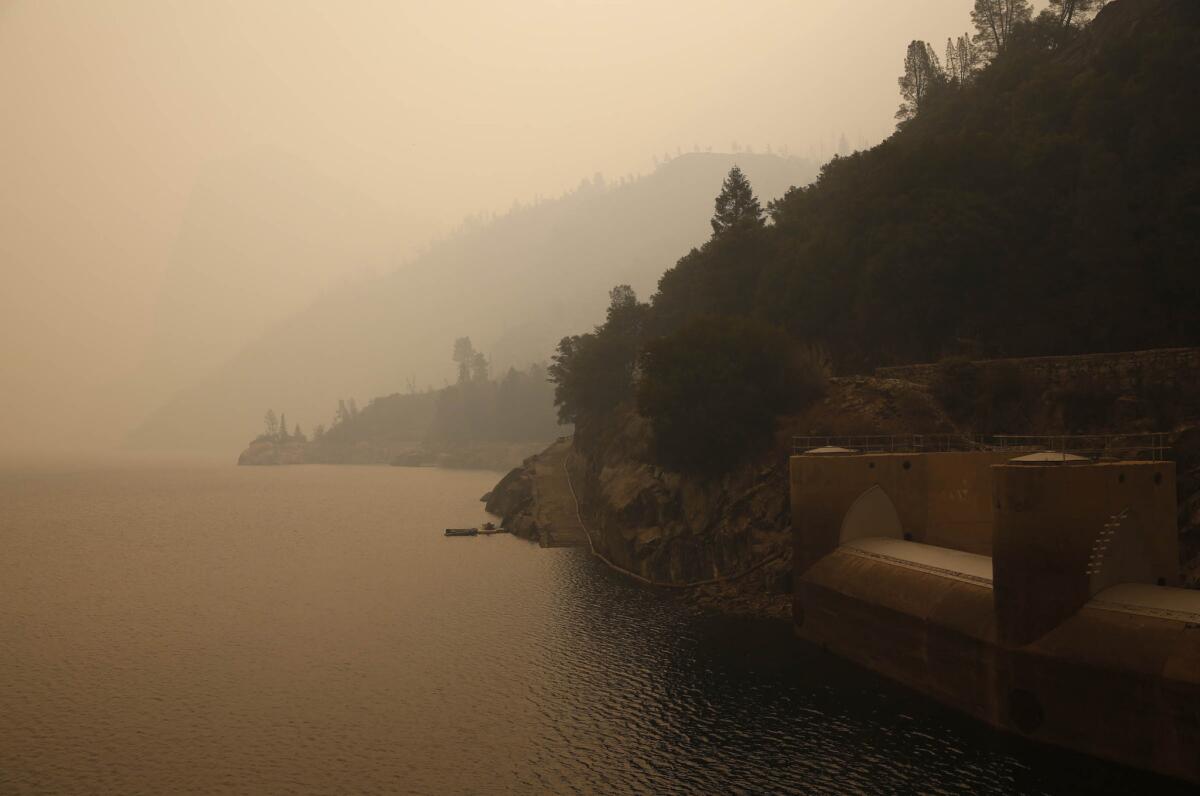 The Hetch Hetchy reservoir and spillway gates on the O'Shaughnessy Dam glow yellow under a fog of dense smoke from the nearby Rim fire.