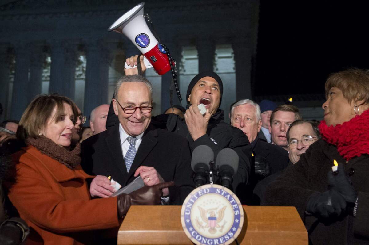 From left, House Minority Leader Nancy Pelosi, Senate Minority Leader Charles E. Schumer, Sen. Cory Booker and other Democratic lawmakers join protesters in Washington on Monday night.