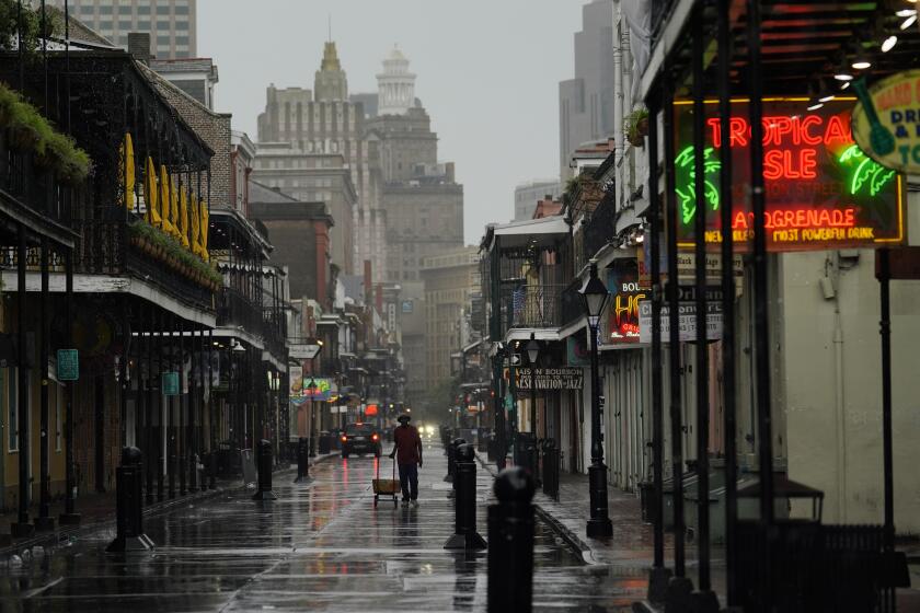 A man pulls a cart down a mostly deserted Bourbon Street in the French Quarter
