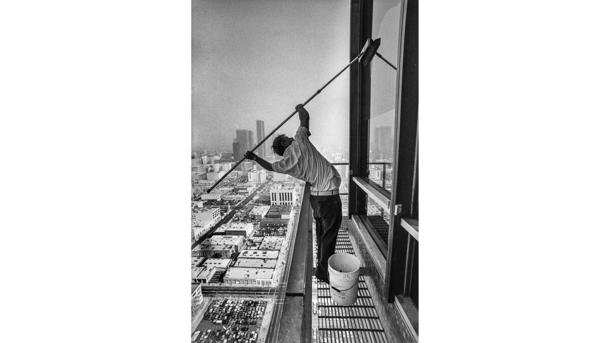 Oct. 28, 1977: Window washer Vince Schaefer leans far out to put a little muscle into job.