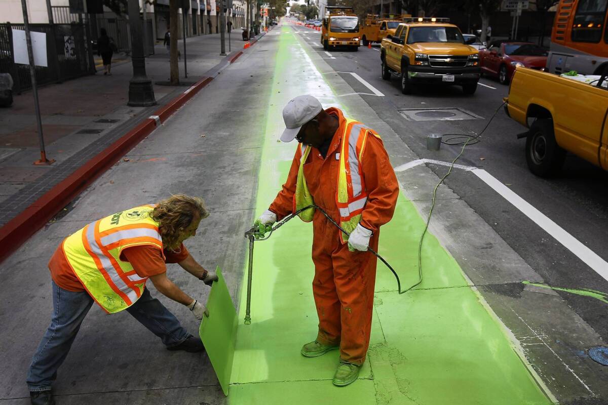 Darryl Strucke and Alvin Pegues, both painters with the L.A. Department of Transportation, create a bike lane along Spring Street in downtown Los Angeles.