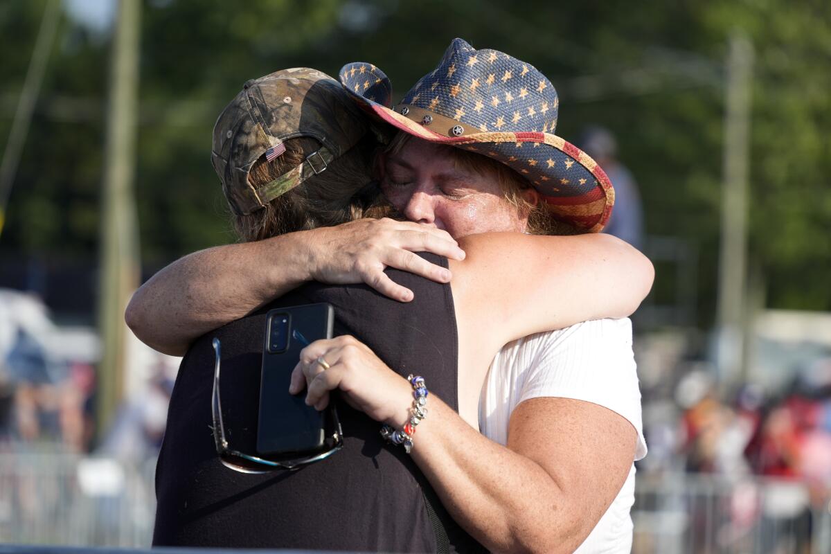 Two people in hats hugging at the rally