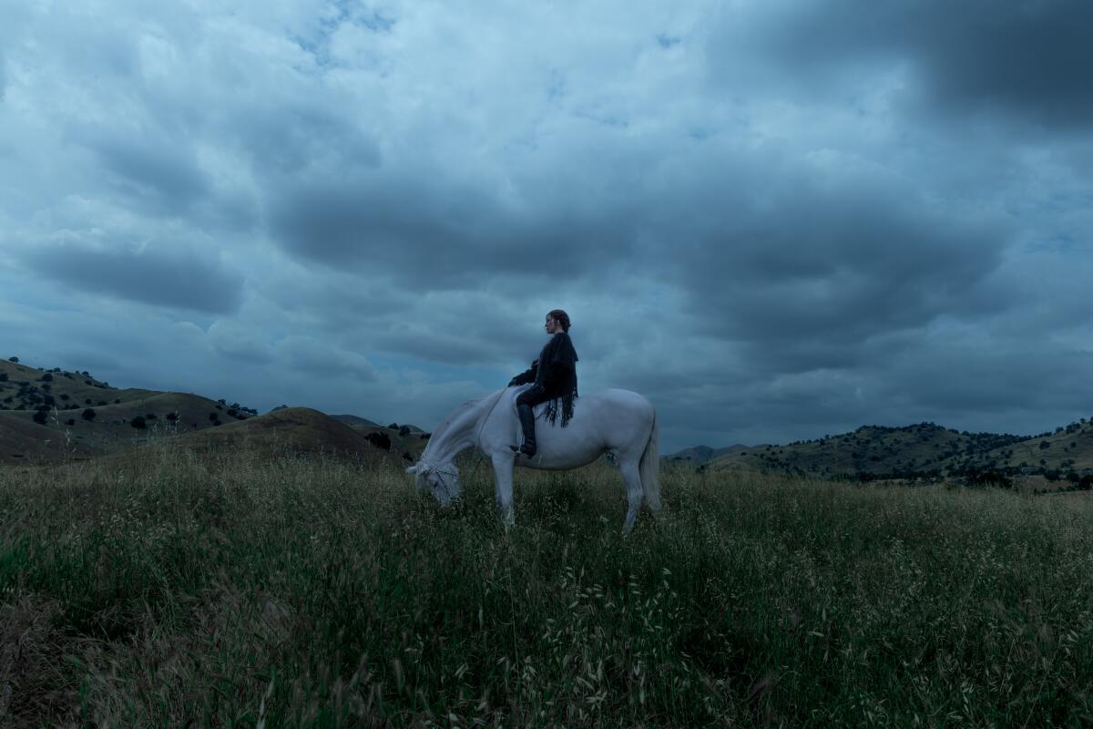 Woman in the distance on a white horse.