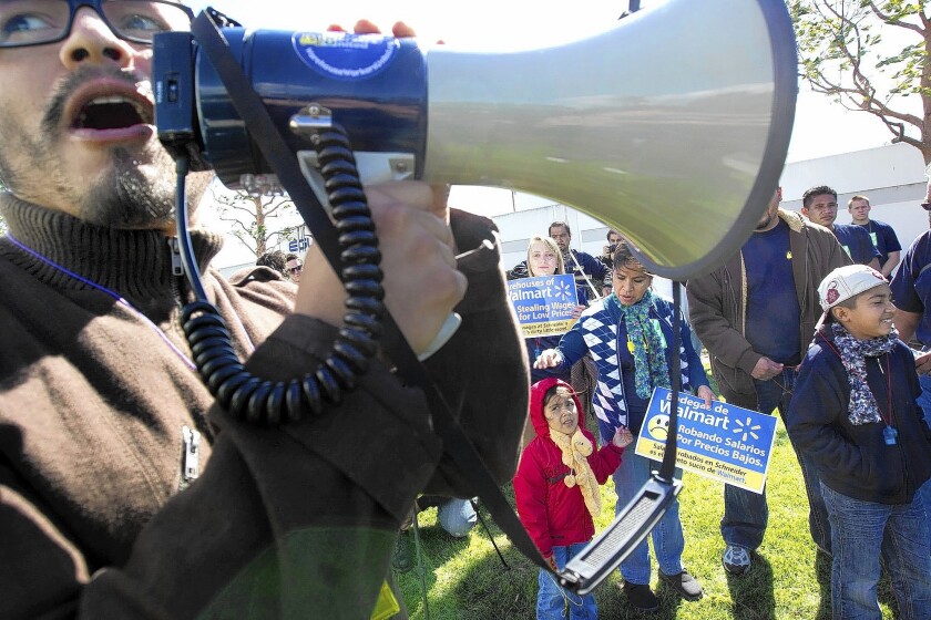 Luis Bocaletti, left, an organizer with Warehouse Workers United, leads the crowd in a chant during a rally to demand action from Wal-Mart outside of Schneider Logistics, a warehouse operator, in 2012.