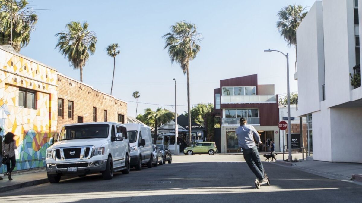 A man rides a motorized Bird scooter toward Abbott Kinney Boulevard in Venice. Los Angeles city officials are considering regulations on where the scooters can be parked.