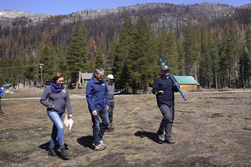 Crossing a meadow normally covered in snow, Karla Nemeth, director of the state Department of Water Resources, left, Wade Crowfoot, Secretary for Natural Resources, second from left, and accompany Sean de Guzman, manager of snow surveys and water supply for the California Department of Water Resources, right, as he conducts the fourth snow survey of the season at Phillips Station near Echo Summit, Calif., on Friday, April 1, 2022. California is experiencing one of the driest starts to spring in decade. Data released Friday showed the water in California’s mountain snowpack sat at 38% of average. (AP Photo/Rich Pedroncelli)