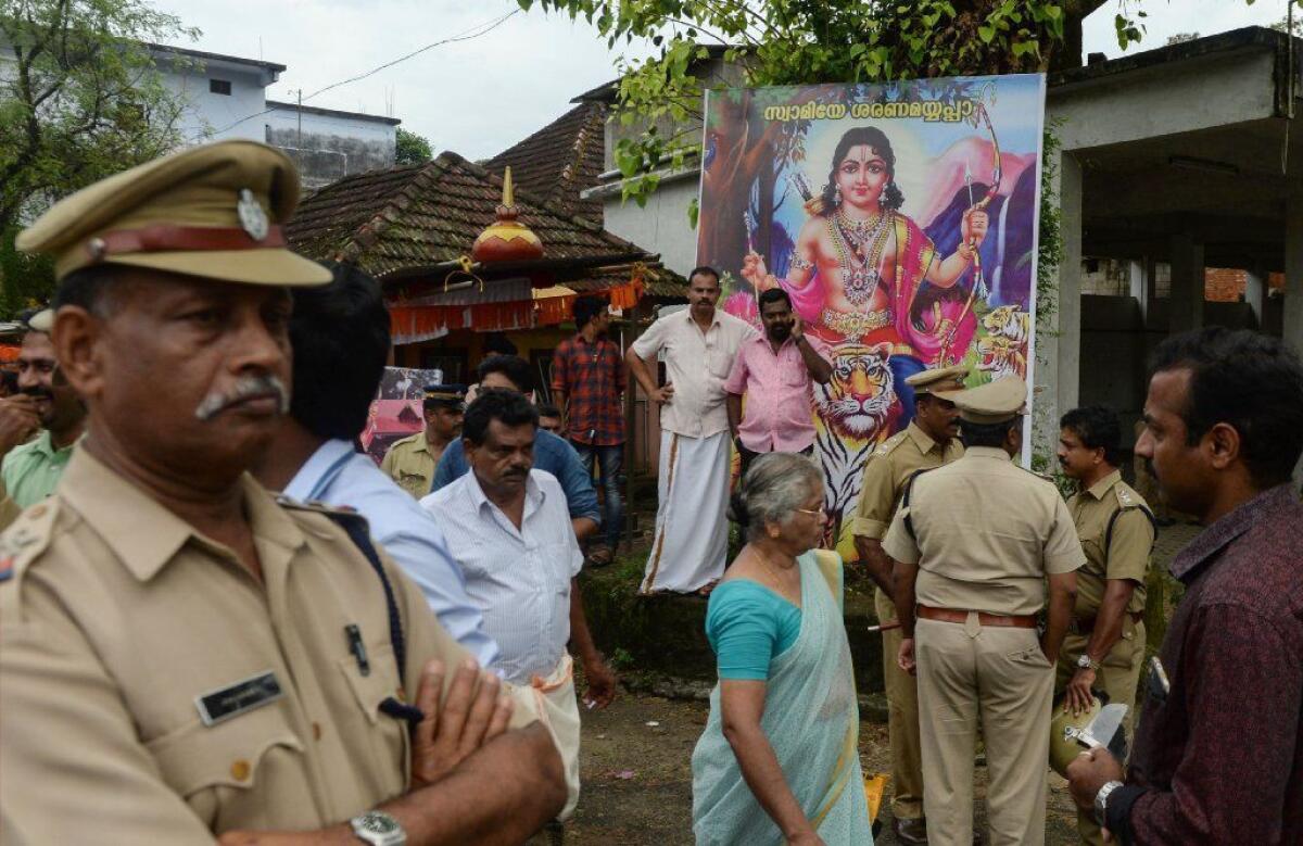 Indian men stand beside a portrait of the Hindu deity Ayyappa outside the Sabarimala temple